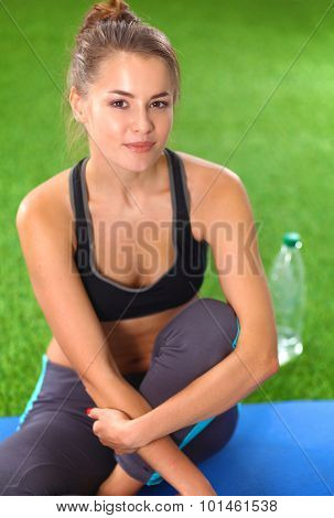 Beautiful young woman relaxing after exerscises on the grass 