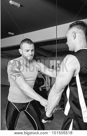 Personal Trainer Helping Man At Gym.