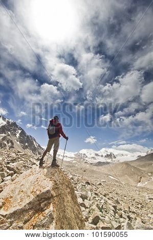 man standing on a cliff in mountains with poles