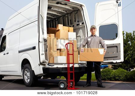 Young delivery man with parcel near cargo truck. Shipping service.