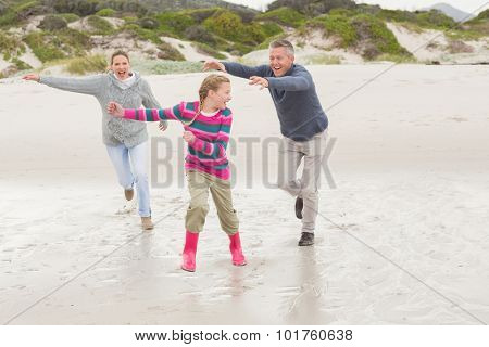 Parents chasing their kid for fun at the beach