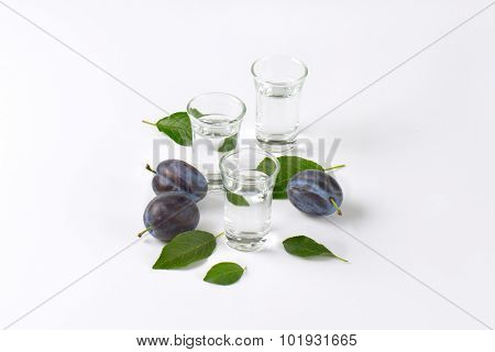 slivovitz (plum brandy) and fresh plums on white background