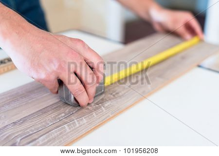 Carpenter measuring piece of wood with tape