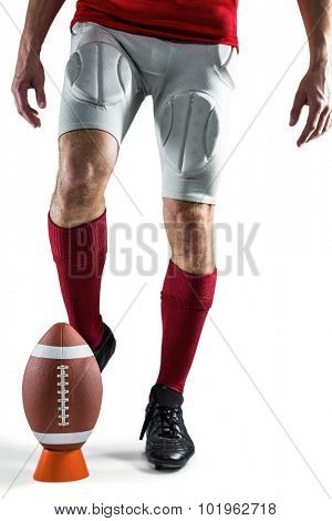 Low section of sports player kicking ball against white background