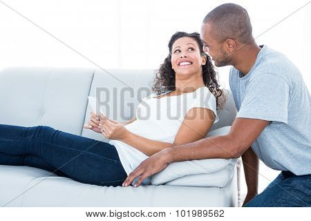 Cheerful young couple looking at each other relaxing at home