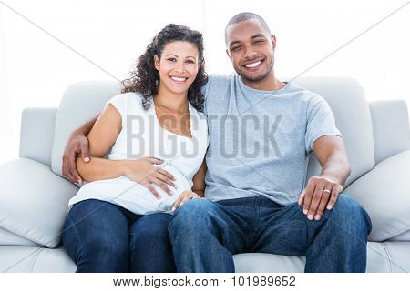 Portrait of cheerful couple sitting on sofa at home