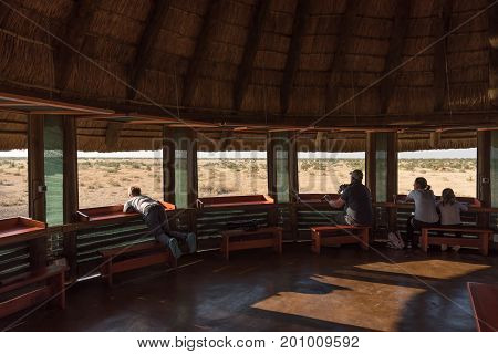 ETOSHA NATIONAL PARK NAMIBIA - JUNE 26 2017: Unidentified tourists in the upper level of the hide at the waterhole at the Olifantsrus Rest Camp in the Etosha National Park
