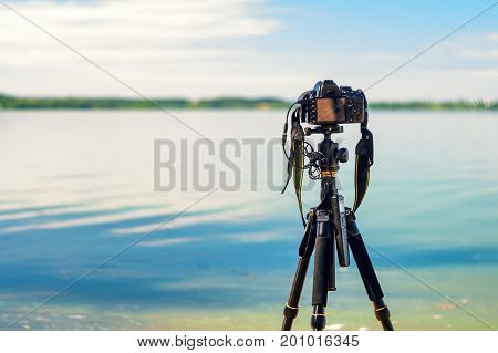 A camera on a tripod on the seashore removes the seascape. Photographic equipment in the process of shooting the landscape