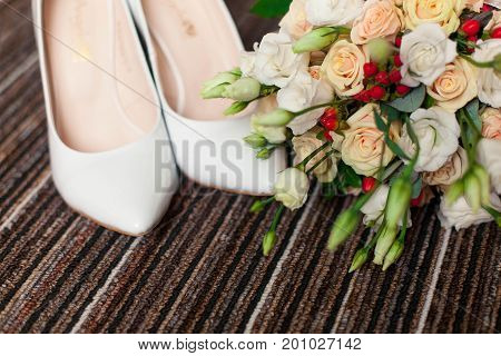 Wedding accessories: shoes and bride's bouquet on carpet