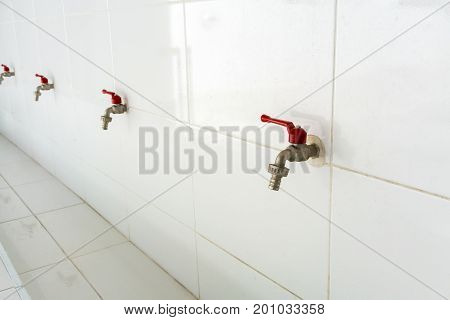 Row of red water taps against white ceramic wall