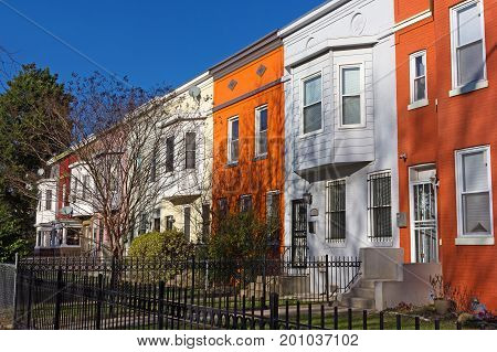 Colorful townhouses under spring sun before sunset Washington DC USA. Historic townhouses in Shaw neighborhood on a quiet street.