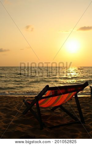 Portrait of a beautiful beach chairs on holidays with sunset on the evening sky at sea and orange sun golden reflection as a abstract background.