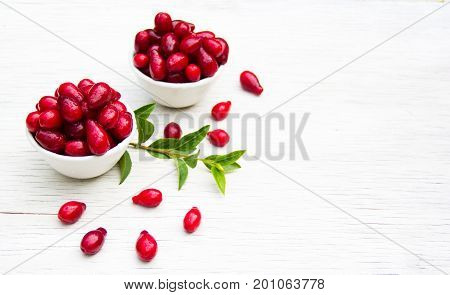 Juicy dogwood in white bowls on a white table. Copy space