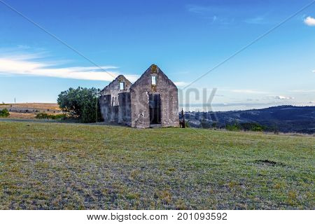 Rural old abandoned derelect farm building on dry winter landscape against blue cloudy sky in Lake Eland Game reserve in South Africa