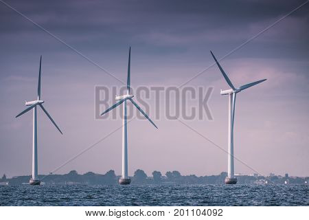 Vertical axis wind turbines generator farm for renewable sustainable and alternative energy production along coast baltic sea near Denmark. Eco power ecology.