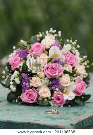 infinity sign of the rings wedding rings on a wood wedding bands wedding rings lie near bouquet of white and pink peach roses a bouquet of roses wedding flowers Selective focus