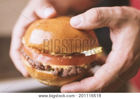 Big burger with beef  in man's hands close-up
