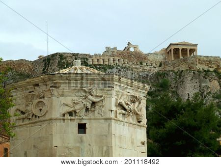 The impressive upper part of the Tower Of The Winds against the ancient Greek temple on the hilltop of Acropolis, Athens, Greece