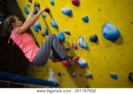 Teenage girl practicing rock climbing in fitness studio