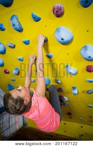Teenage girl practicing rock climbing in fitness studio