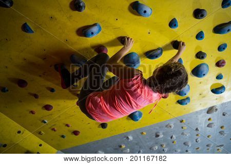 Teenage girl practicing rock climbing in fitness studio