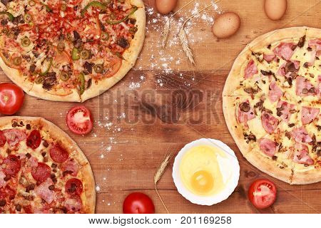 Pizza on wooden. Wooden table top view. On the table are the food for cooking. Healthy food. Dietetic foods. Above view on food. Hot Homemade Pepperoni Pizza Ready to Eat