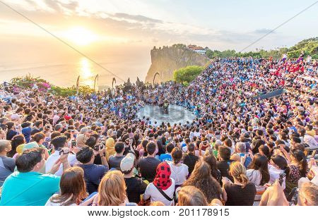 Bali, Indonesia - August 24, 2017: Tourists watch traditional Balinese Kecak Dance at Uluwatu Temple on Bali, Indonesia. 
Kecak Dance at Uluwatu Temple on Bali is very popular cultural show on Bali.