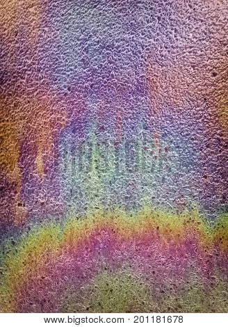 spilled oil on a tarmac road reflecting rainbow slick colors after the rain
