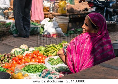 JAISALMER RAJASTHAN INDIA - MARCH 07 2016: Horizontal picture of indian woman selling vegetables at the street market in Jaisalmer known as Golden City in India.