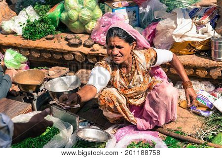 JAISALMER RAJASTHAN INDIA - MARCH 07 2016: Horizontal picture of indian woman giving money at the street market in Jaisalmer known as Golden City in India.