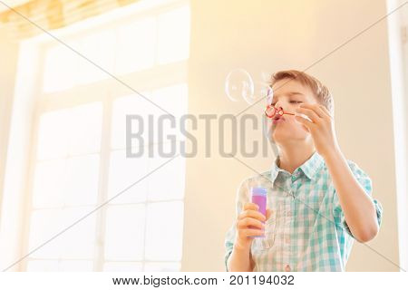 Boy blowing bubbles at home