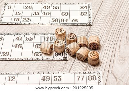 Board Game Lotto On White Desk. Wooden Lotto Barrels And Game Cards