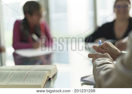 Woman in office, working with some sheets, pen and smartphone and pen in her hand. Blurred background.
