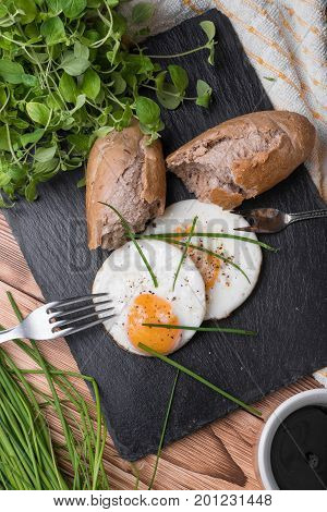 Roeasted Round Eggs with Fresh Bread on Black Stone Board with Herbs