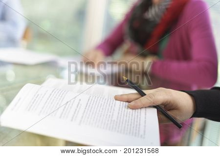 Woman in office, working with some sheets, pen and smartphone and pen in her hand. Blurred background.