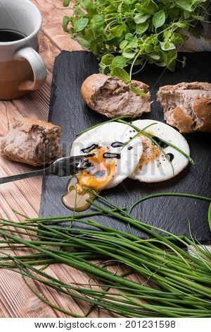 Roeasted Round Eggs with Fresh Bread on Black Stone Board with Herbs