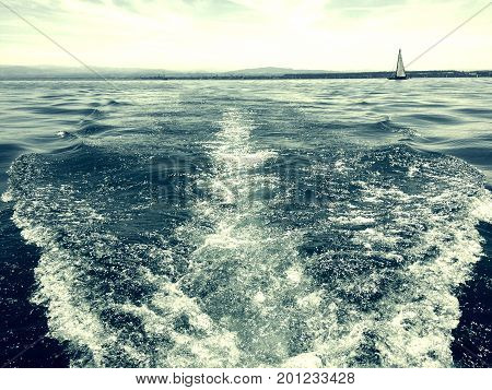 Wellen auf See durch Motorboot verursacht mit Segelboot im Hintergrund