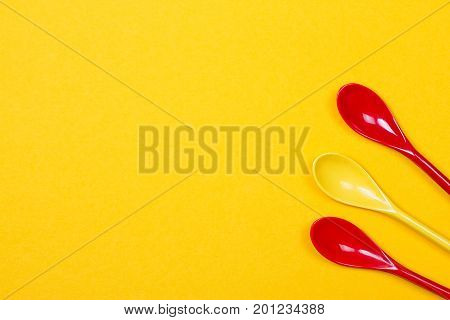 Set of multi-colored long spoons on a yellow background