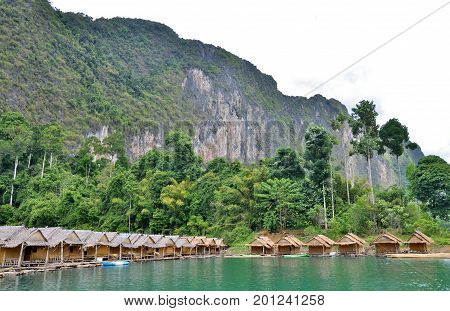 Traditional Thai bamboo house resort, floating among mountains view, clear sky and clear water in the Cheow Lan Dam (Ratchaprapa Dam) at Khao Sok National Park, Surat Thani Province, Thailand.