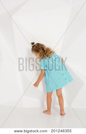 Beautiful little fashion model on white studio background. Portrait of cute girl posing in studio. Little blonde in bright summer dress