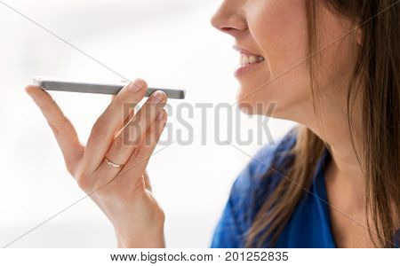 technology, communication and people concept - close up of happy woman using voice command recorder on smartphone