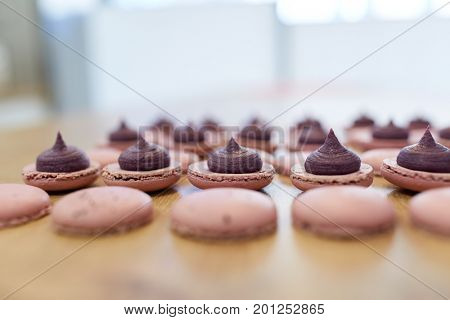 cooking, confectionery and baking concept - macarons with buttercream filling on table at bakery