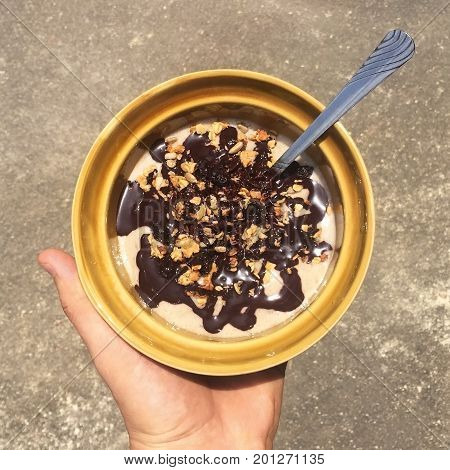Chocolate Banana Raw Vegan Smoothie Bowl. Hand Holding Plate with Healthy Organic Breakfast. Thailand.