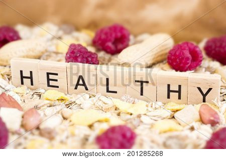 The word "Healthy" is standing on the lots of corn and oatmeal flakes.  Healthy lifestyle concept.