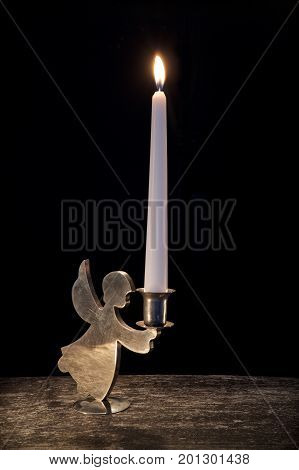 burning candle in vintage candlestick on black background