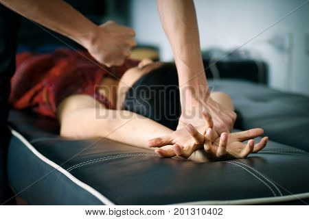 Close up man's hand holding a woman hands over a black couch for rape and sexual abuse concept.