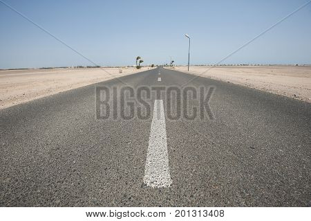 Long straight desert road in remote arid landscape going to infinity vanishing point