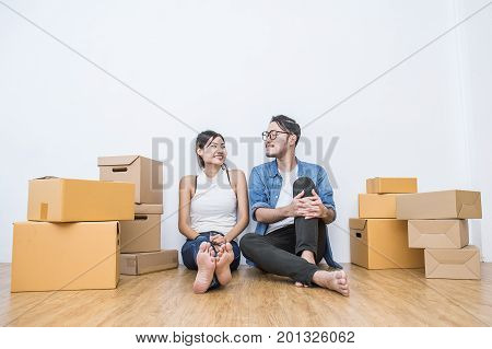 Young couple packing and moving their house. SME or freelance woman and man siting on the floor working at home concept online marketing packaging and delivery SME concept