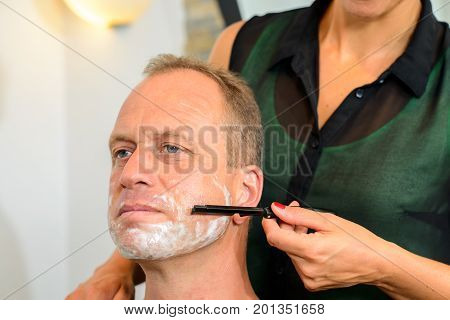 Female Hairdresser Shaving  Beard Of Man