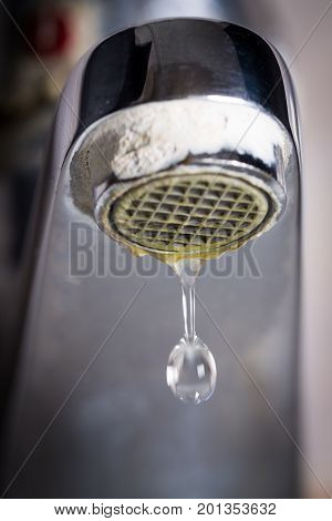 Old leaking faucet with stone and calcium sediments due to hard water.
